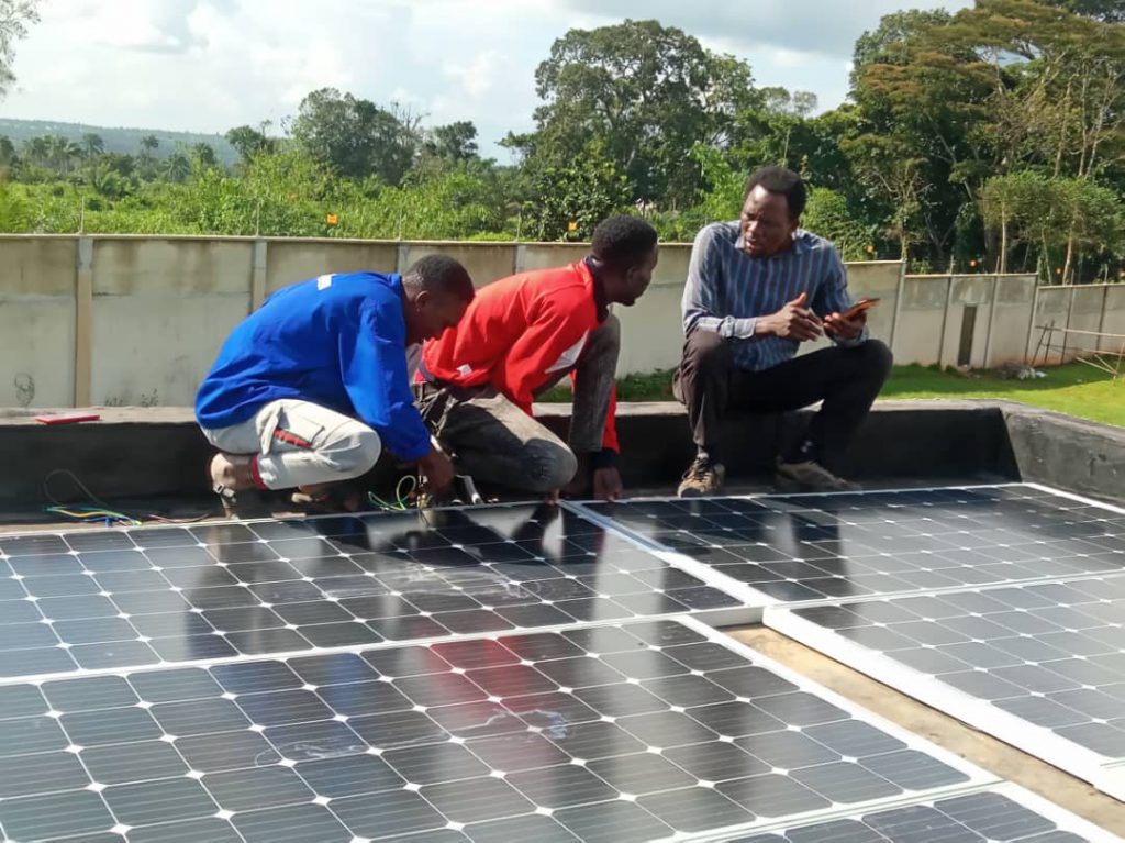 3 men working next to solar panel