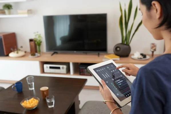 woman operating tablet in sitting room in front of wide screen television